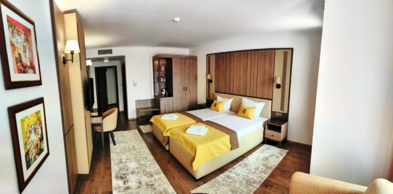 Habitación doble deluxe con cama grande y decoración en tonos dorados en Spa Complex Aleksandar