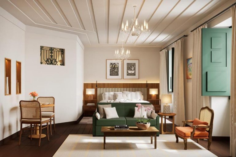 Suite elegante con cama, sofá verde y chandelier del Hotel Villa Bahia en Salvador de Bahía