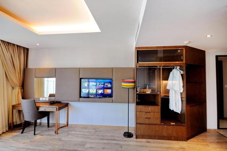 Habitación moderna con armario de madera, escritorio y TV del Panorama Nha Trang Condotel by One