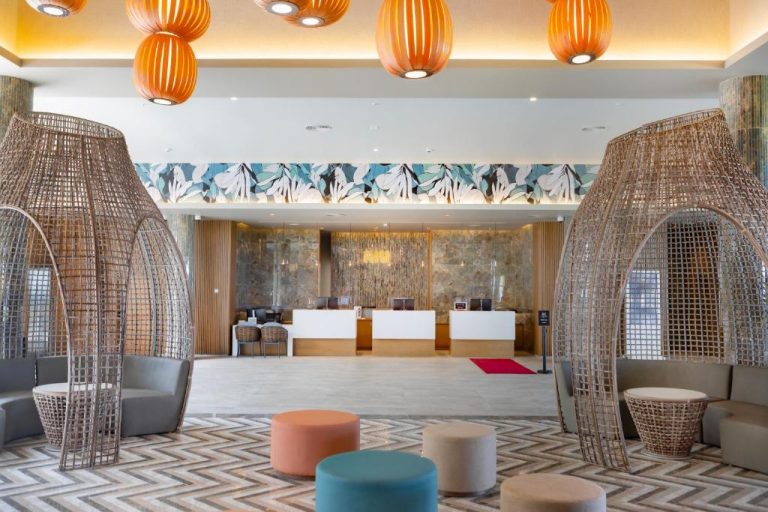 Recepción y lobby tropical del Riu Palace Mauritius con decoración de ratán y lámparas naranjas