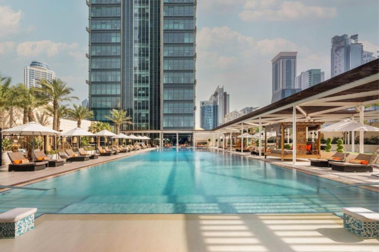 Piscina exterior con tumbonas y sombrillas del Marriott Marquis City Center Doha con vistas a los rascacielos