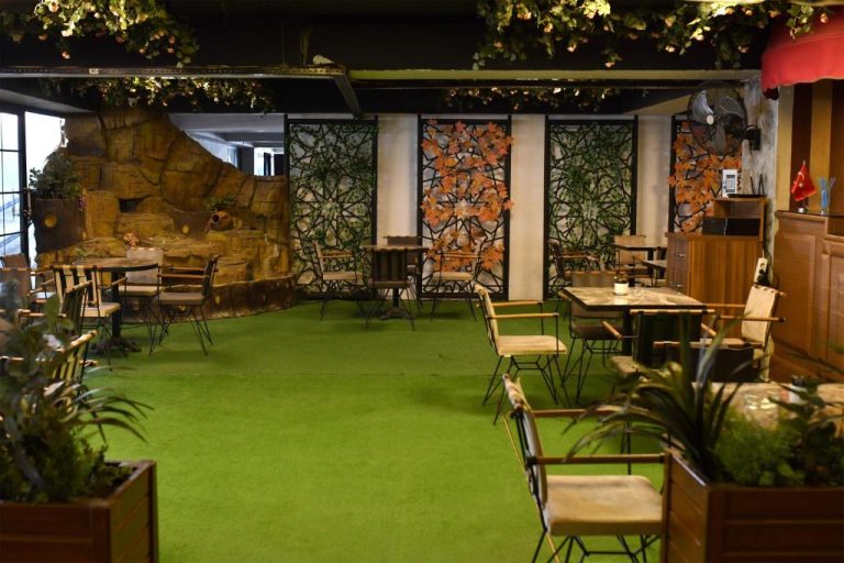 Restaurante interior temático con césped artificial y decoración de jardín natural en Royal Hotel Inegol