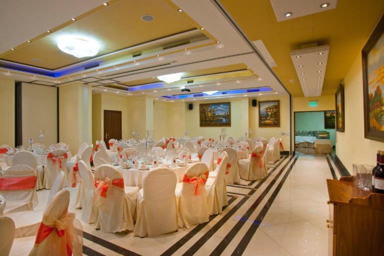 Salón de banquetes elegante del Semeli Hotel con mesas decoradas y sillas blancas con lazos rosas