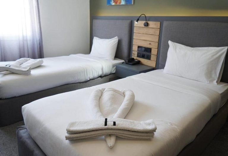 Habitación triple del Aitch Boutique Hotel con camas individuales y decoración de toallas en forma de cisne