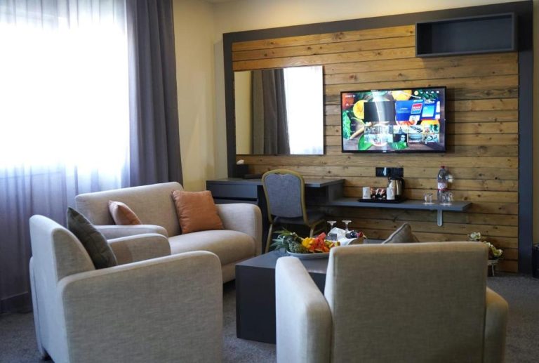 Salón moderno con Smart TV y pared de madera en Aitch Boutique Hotel, sillones cómodos y mesa de centro