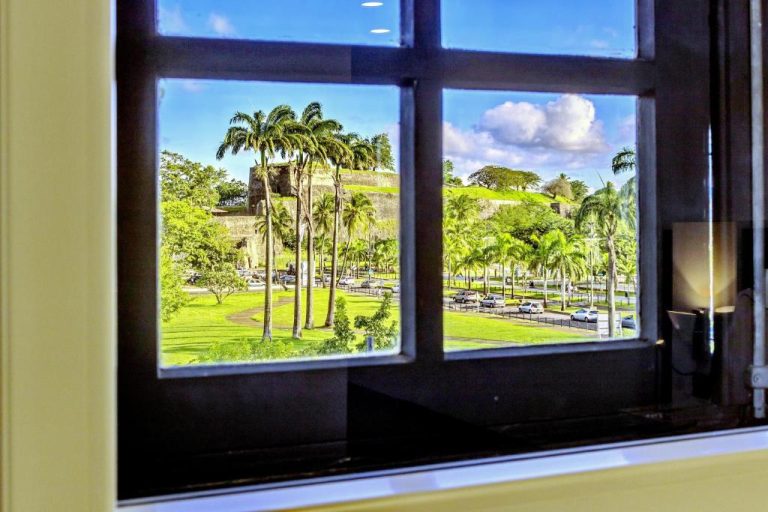 Vista desde ventana del Residence Fort Savane con fuerte histórico, palmeras y jardines verdes