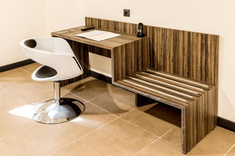 Escritorio de madera con teléfono y silla moderna en habitación del Residence Fort Savane