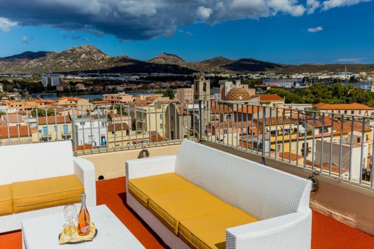 Terraza con sofás blancos y vistas panorámicas a la ciudad y montañas del Hotel Panorama