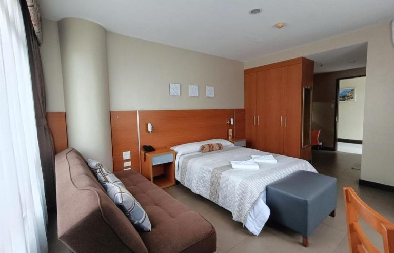 Habitación suite con cama doble y sofá en Fuente Oro Business Suites Cebu