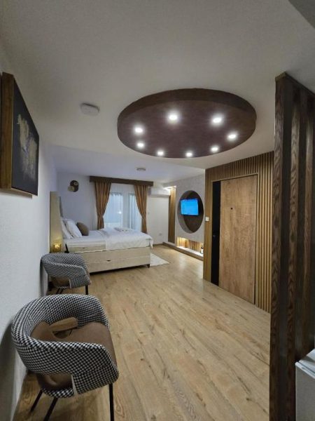 Habitación suite moderna con cama doble, suelo de madera y techo iluminado en Hotel Mažijanik