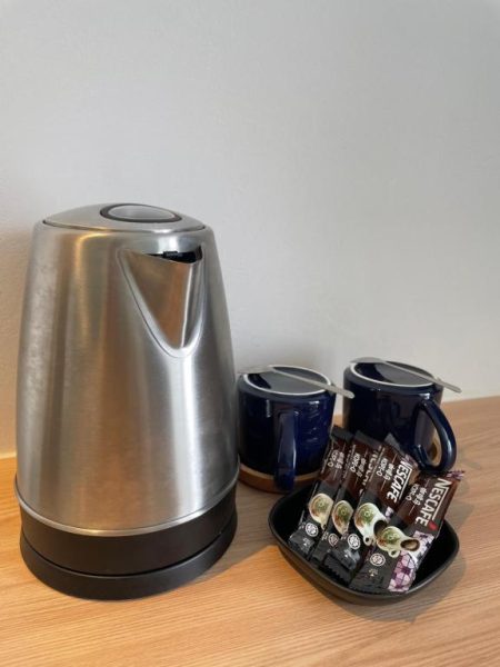 Hervidor eléctrico de acero y tazas azules con café Nescafé en apartamento Getawayhub Roxy Sematan Beach