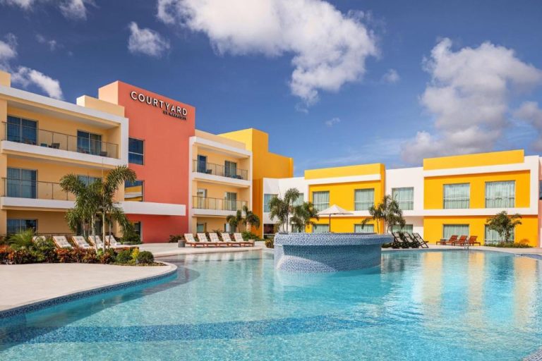 Piscina exterior con fuente y tumbonas del Courtyard by Marriott Curacao bajo cielo azul