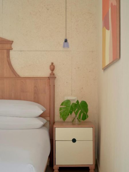 Habitación elegante con cama y mesita de noche con planta monstera en Kimpton Las Mercedes by IHG