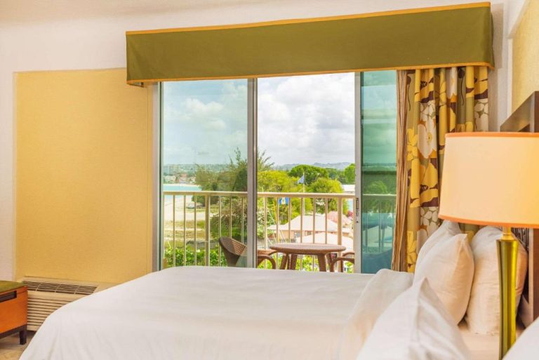 Habitación con cama doble y balcón con vista al jardín y playa en Radisson Aquatica Resort Barbados