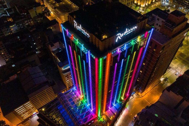 Fachada nocturna iluminada con luces de colores del Radisson Montevideo Victoria Plaza Hotel vista aérea