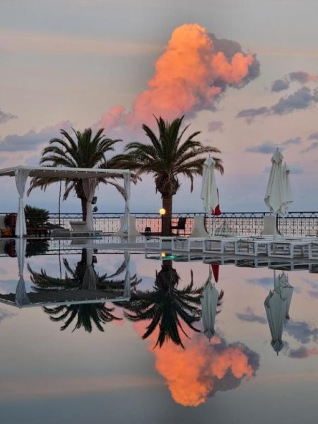 Piscina infinita con palmeras y reflejo del atardecer en Delta Hotels by Marriott Giardini Naxos