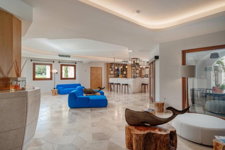 Lobby moderno del Hotel Sestante con sofás azules, esculturas de ballenas en madera y zona de bar