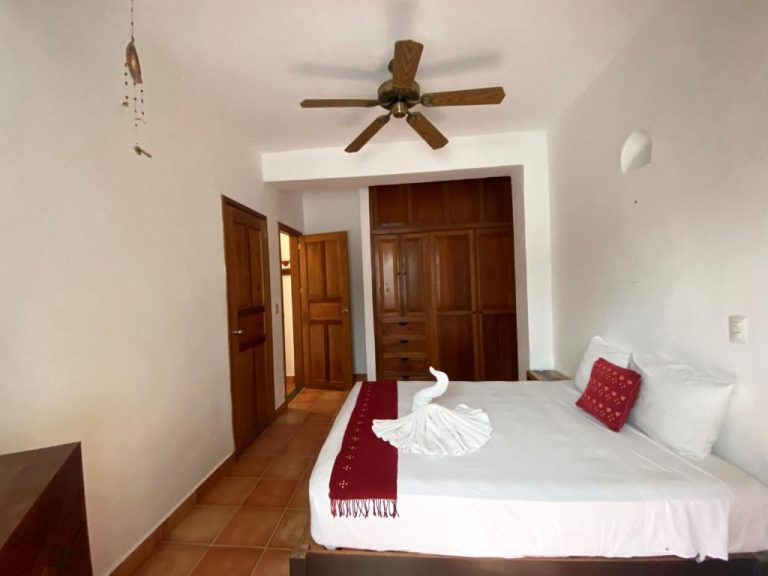 Habitación doble con cama king, abanico de techo y armario de madera en Zihil Ha Hotel