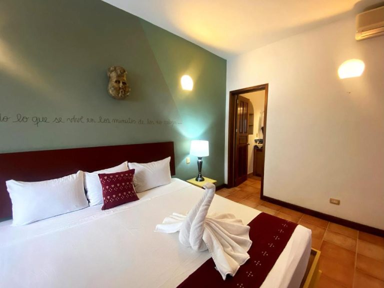 Habitación doble con cama king y decoración colonial en Zihil Ha Hotel, con toallas artísticas