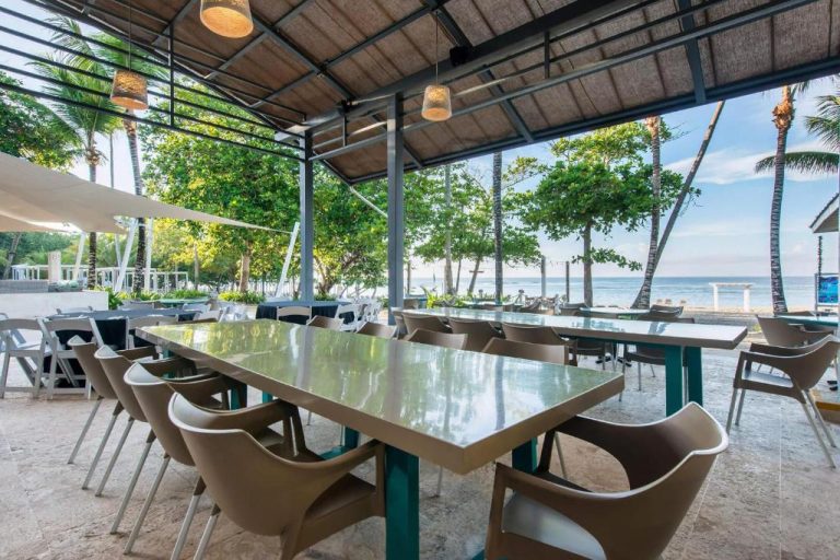 Restaurante frente al mar con mesas y vistas a la playa en Emotions by Hodelpa Juan Dolio