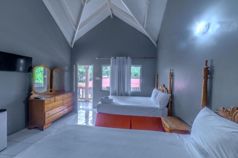 Habitación doble con techo a dos aguas y camas con cabeceros de madera en Tamboo Resort