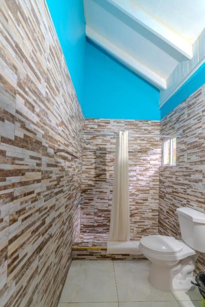 Baño con azulejos de piedra natural, ducha con cortina y techo azul en Tamboo Resort