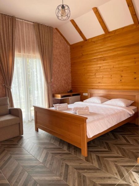 Habitación doble con cama de madera y pared de troncos en Etno Selo Tačevine