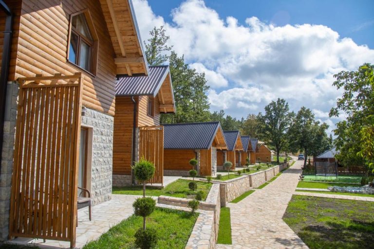 Cabañas de madera con tejado metálico y jardín empedrado en Etno selo Tačevine