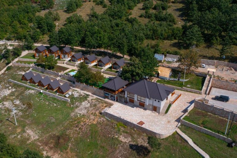 Vista aérea de las cabañas de madera y edificio principal del Etno selo Tačevine rodeado de naturaleza