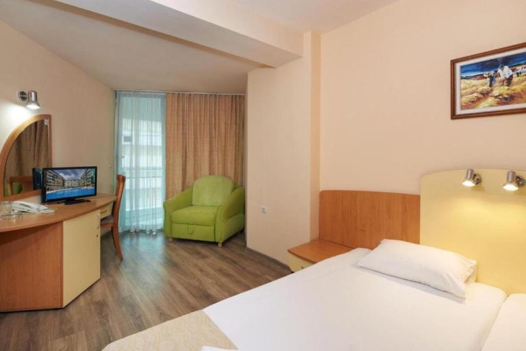 Habitación doble con escritorio, televisión y sillón verde en Diamond Hotel Sunny Beach All Inclusive