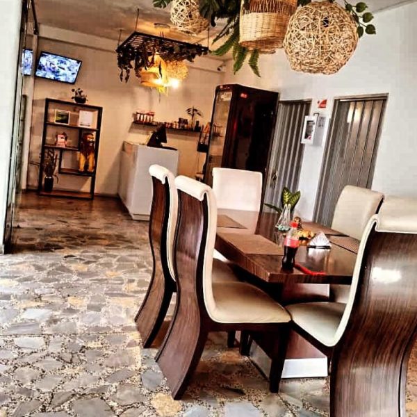 Restaurante interior del Hotel Bayadera Real con mesas de madera, sillas elegantes y decoración con lámparas de mimbre