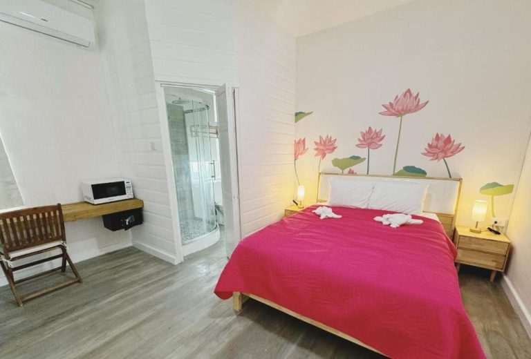 Habitación doble con cama roja y mural de flores de loto en Eden On the Sea