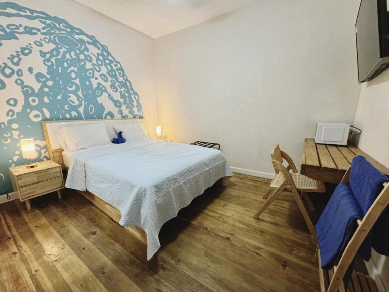 Habitación doble con mural de olas azules y suelo de madera en Hotel Eden On the Sea