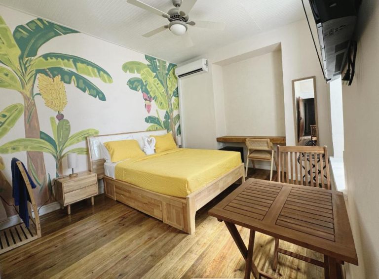 Habitación doble con mural tropical y cama amarilla en Hotel Eden On the Sea