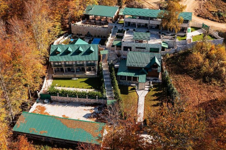 Vista aérea del Garni Hotel Elite Resort rodeado de bosque otoñal con tejados verdes y jardines