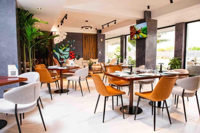 Restaurante moderno del Habana Hotel con mesas elegantes, sillas naranjas y decoración tropical