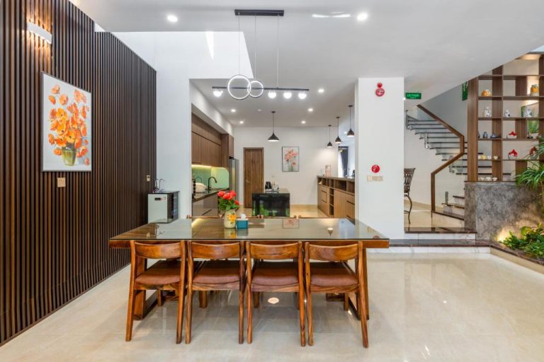 Comedor moderno con mesa de cristal y cocina abierta en Hai Hội Villa Hoi An