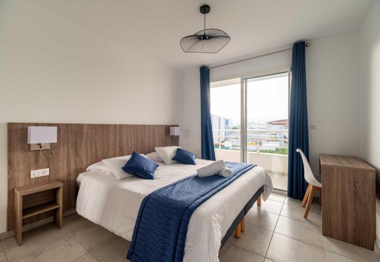 Habitación doble con cama king y decoración en azul y madera en B&B HOME Fort-de-France Marina