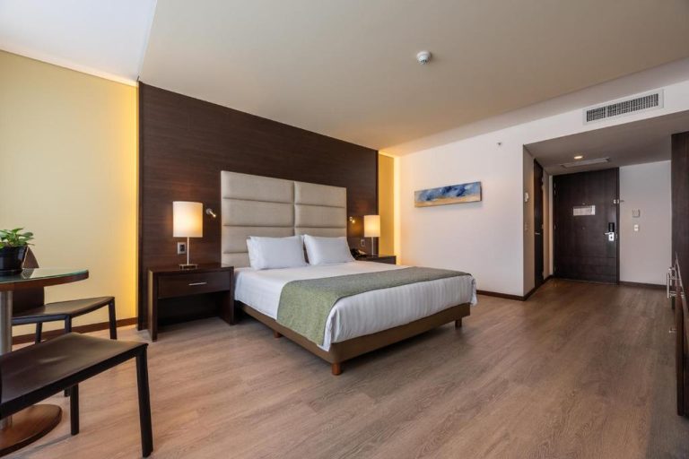 Habitación king size con suelo de madera y cabecero tapizado en Hotel Estelar Milla De Oro