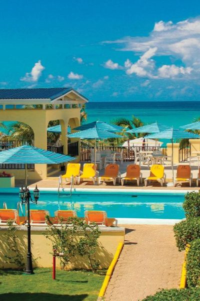 Piscina exterior con tumbonas y vistas al mar turquesa en Rooms on the Beach Negril, Jamaica