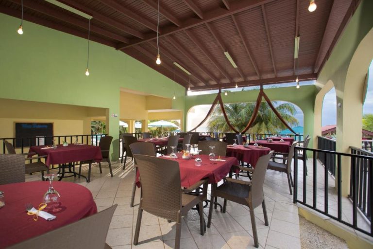 Restaurante terraza con vistas al mar y mesas con manteles rojos en Rooms on the Beach Negril