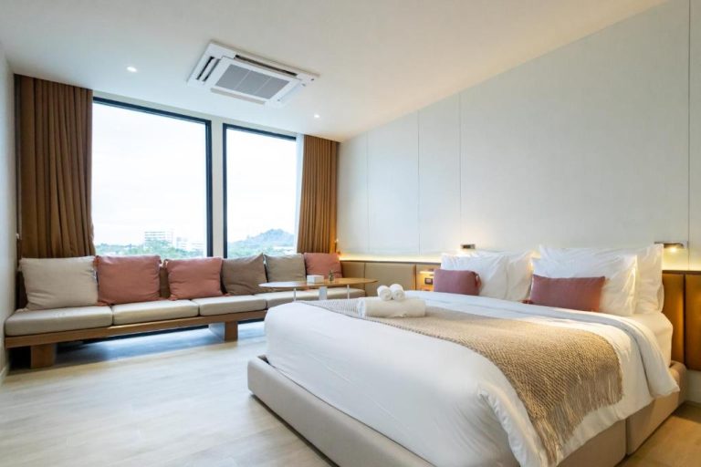 Habitación suite con cama king size y sofá en el Good Nakhonsawan Hotel con vistas a la ciudad