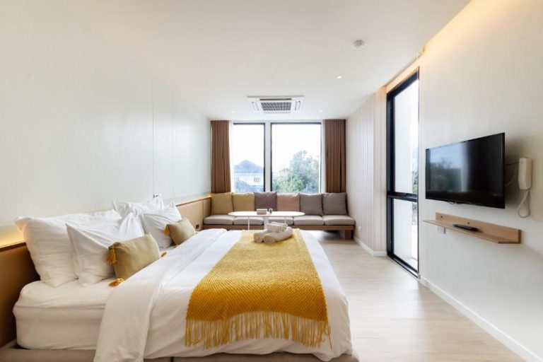 Habitación deluxe con cama doble y sofá en Good Nakhonsawan Hotel, amplia y luminosa