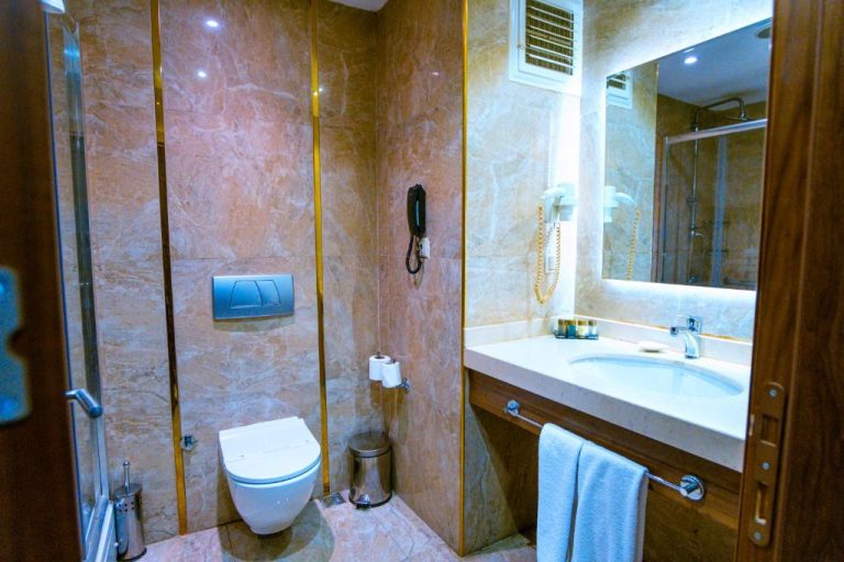 Baño de lujo con paredes de mármol, inodoro suspendido y lavabo en el Royal Hotel Inegol