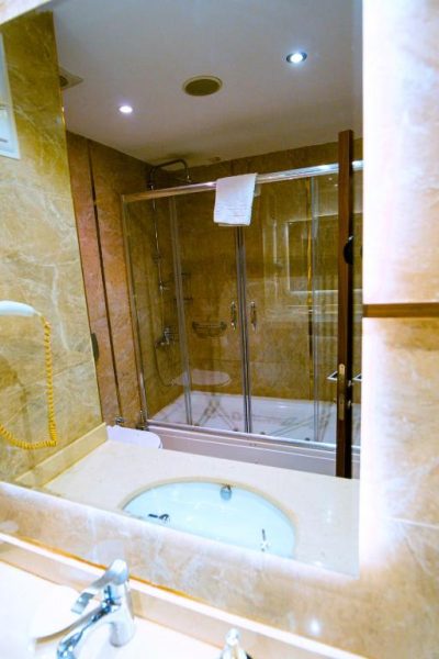 Baño de lujo con ducha de cristal y revestimiento de mármol en Royal Hotel Inegol
