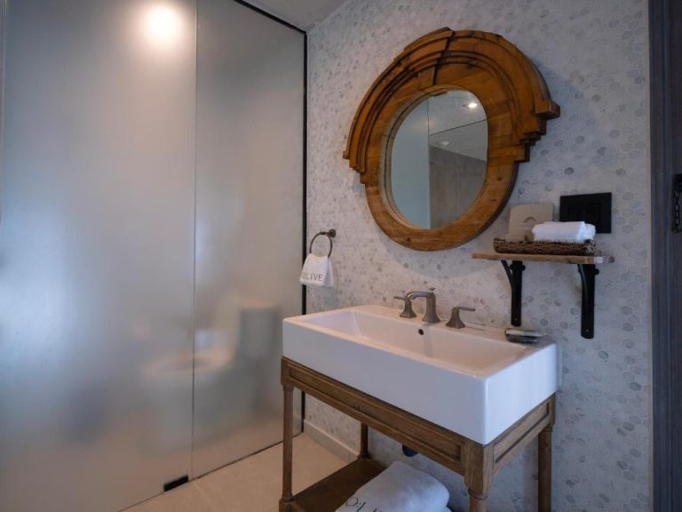 Baño elegante con lavabo blanco y espejo de madera artesanal en O:Live Boutique Hotel