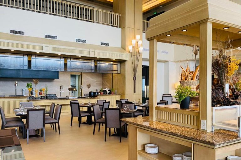 Restaurante buffet elegante con mesas y decoración tropical en Timberland Highlands Resort