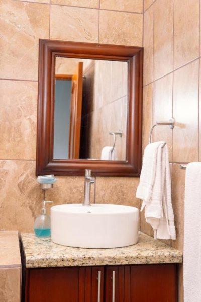 Baño moderno con lavabo sobre encimera de mármol y espejo de madera en Hotel Real Paraíso