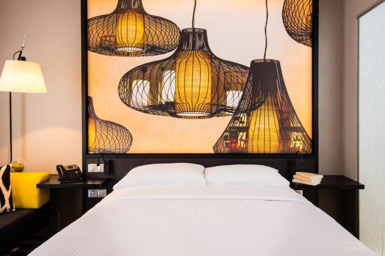 Habitación doble del Simon Hotel con gran mural de lámparas orientales y cama matrimonial con ropa blanca