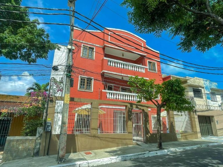 Fachada exterior roja de Refúgio Pousada Fortaleza con balcones y rejas blancas en la calle